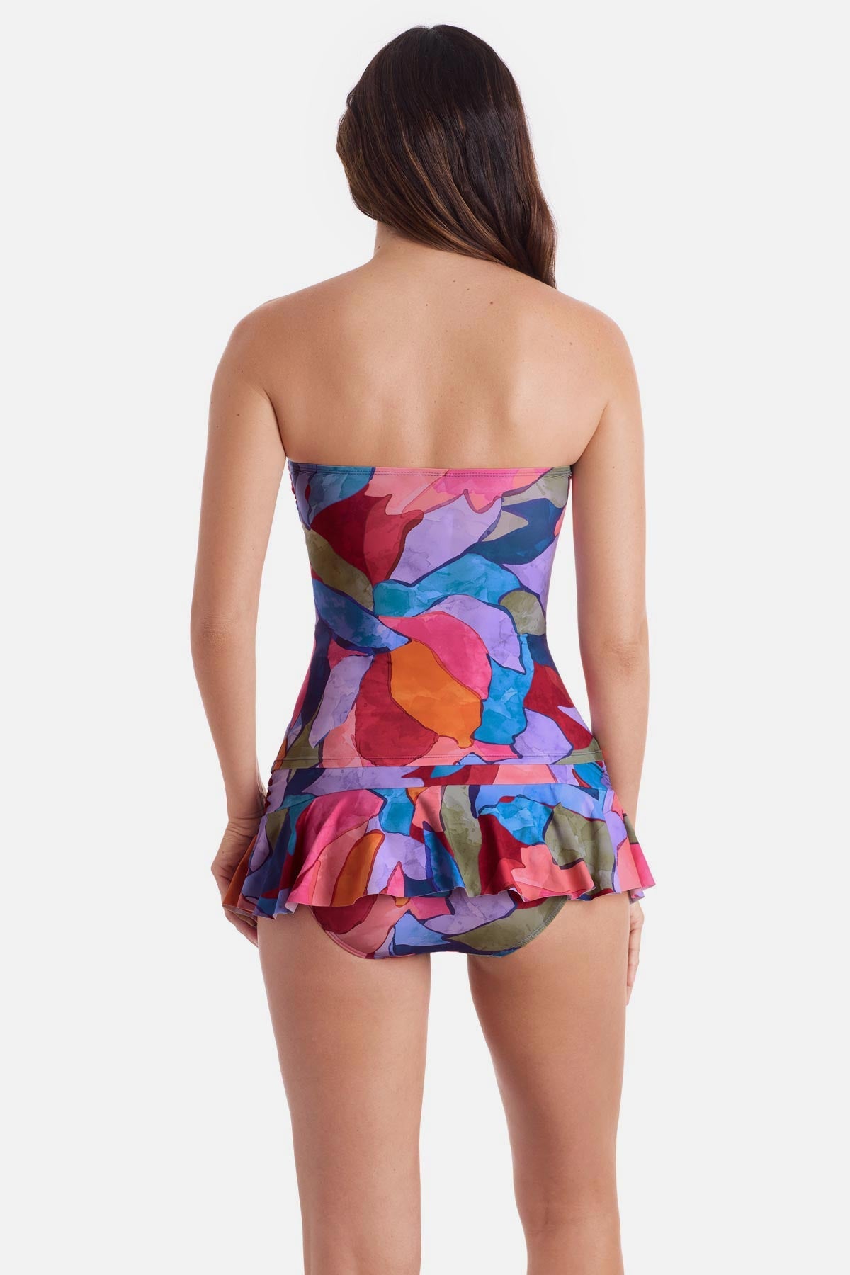Woman turned away wearing a bandeau style multicolored abstract print tankini top with matching skirted swim bottoms