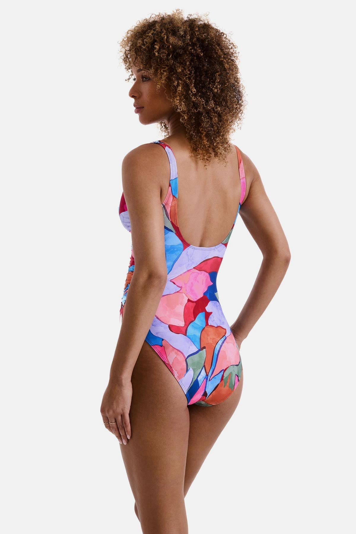 Woman turned left wearing a multicolored abstract print one-piece swimsuit