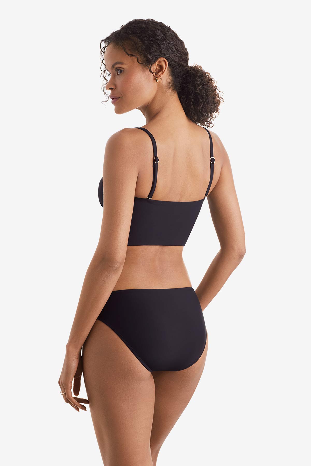 Woman faced left wearing a black midkini swim top with black swim bottoms