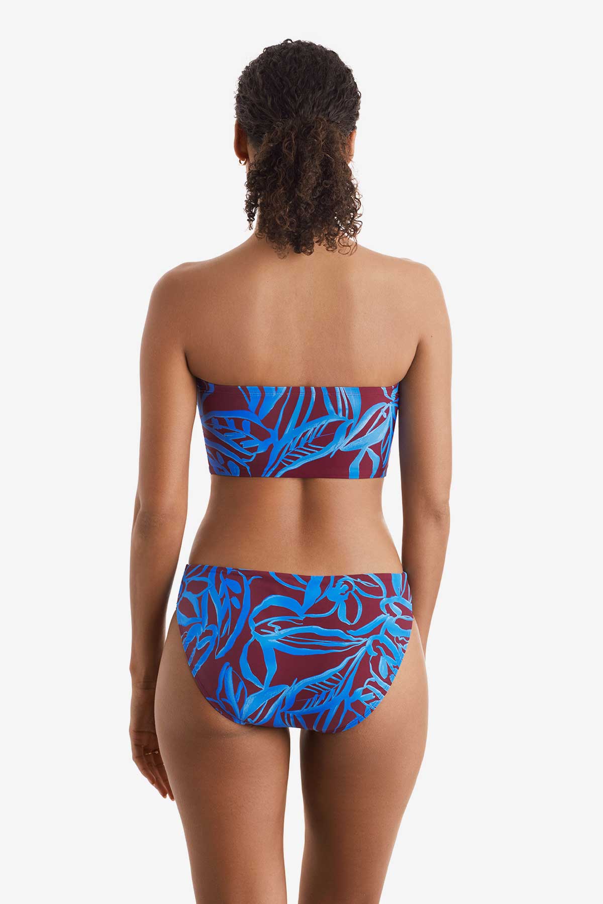 Woman faced away wearing a blue and brown abstract floral printed midkini swim top with matching swim bottoms