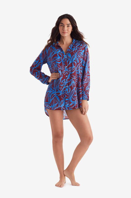 Woman wearing a button down long sleeve shirt with blue and brown abstract floral print
