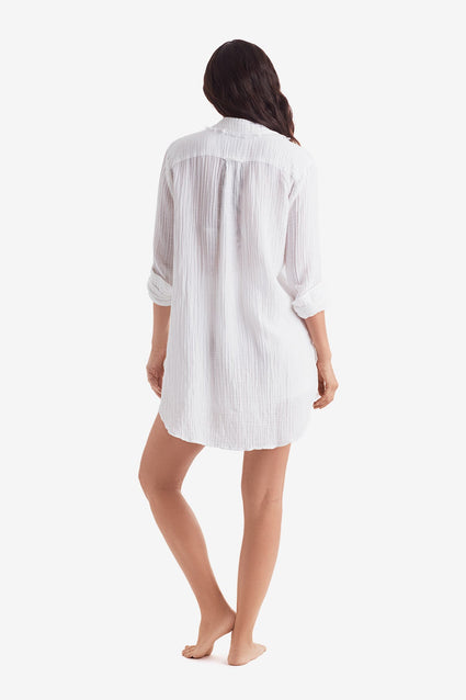 Woman turned away wearing a white long sleeve button up shirt