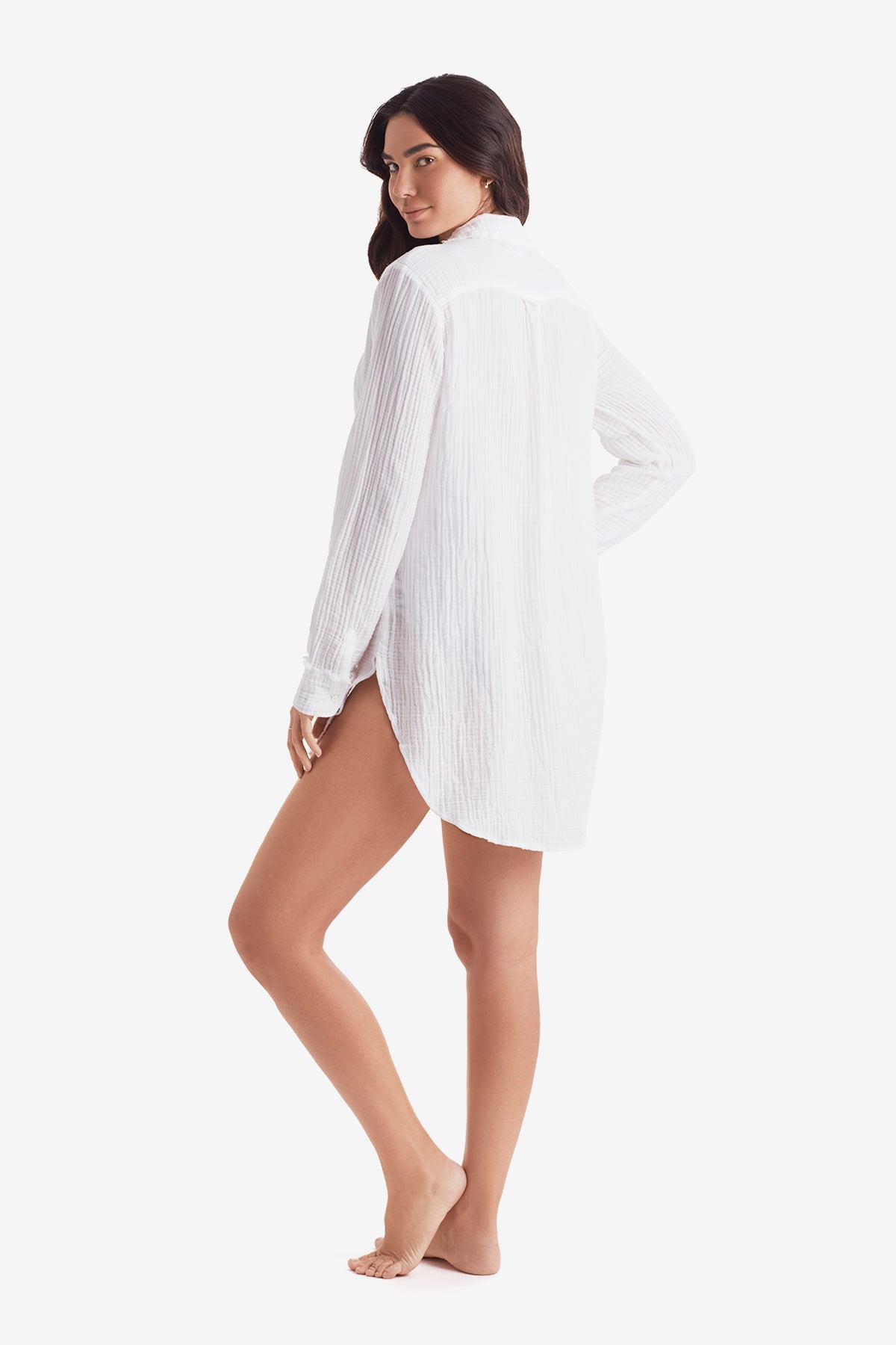 Woman turned left wearing a white long sleeve button up shirt