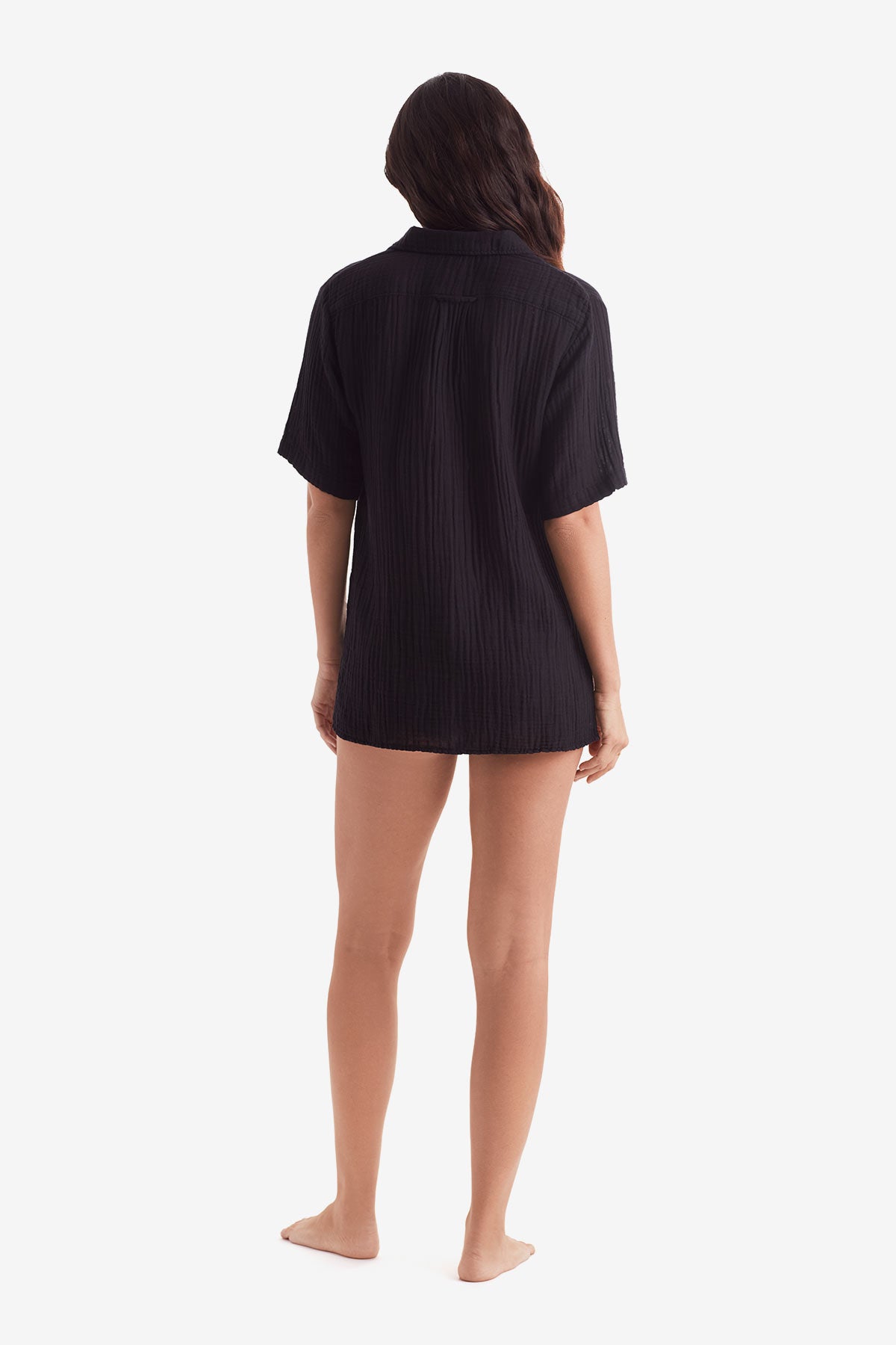 Woman faced away wearing a black short sleeve button up shirt