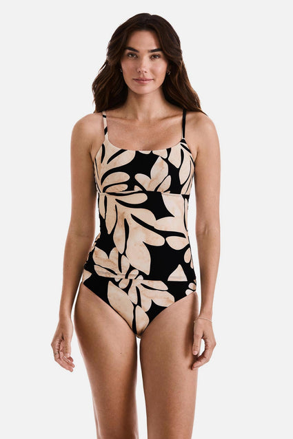 Woman wearing a large tan and black leaf printed tankini top with matching swim bottoms