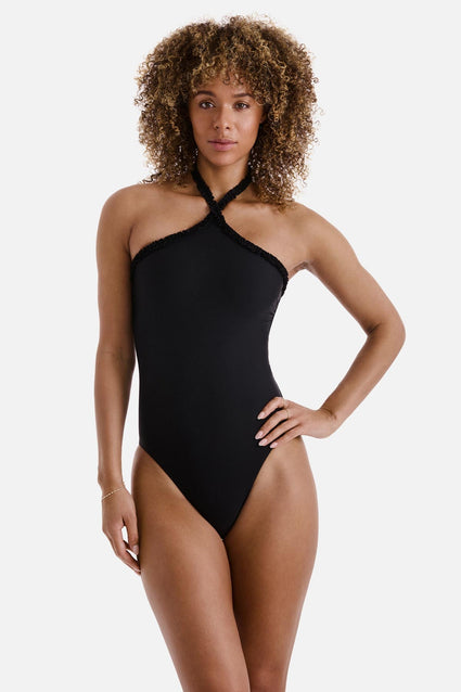 Woman wearing a black high neck one-piece swimsuit with frills along the edges