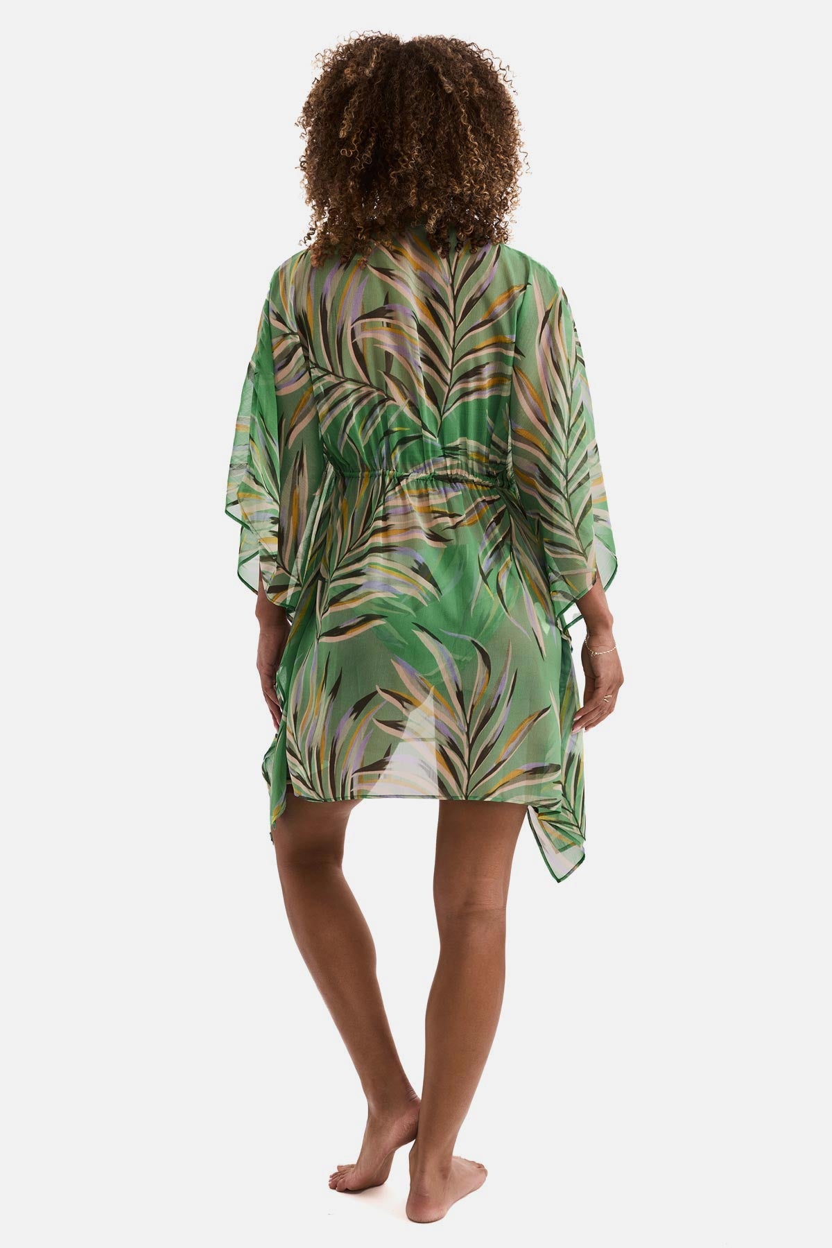 Woman turned away wearing a multicolored leaf print sheer swim cover up