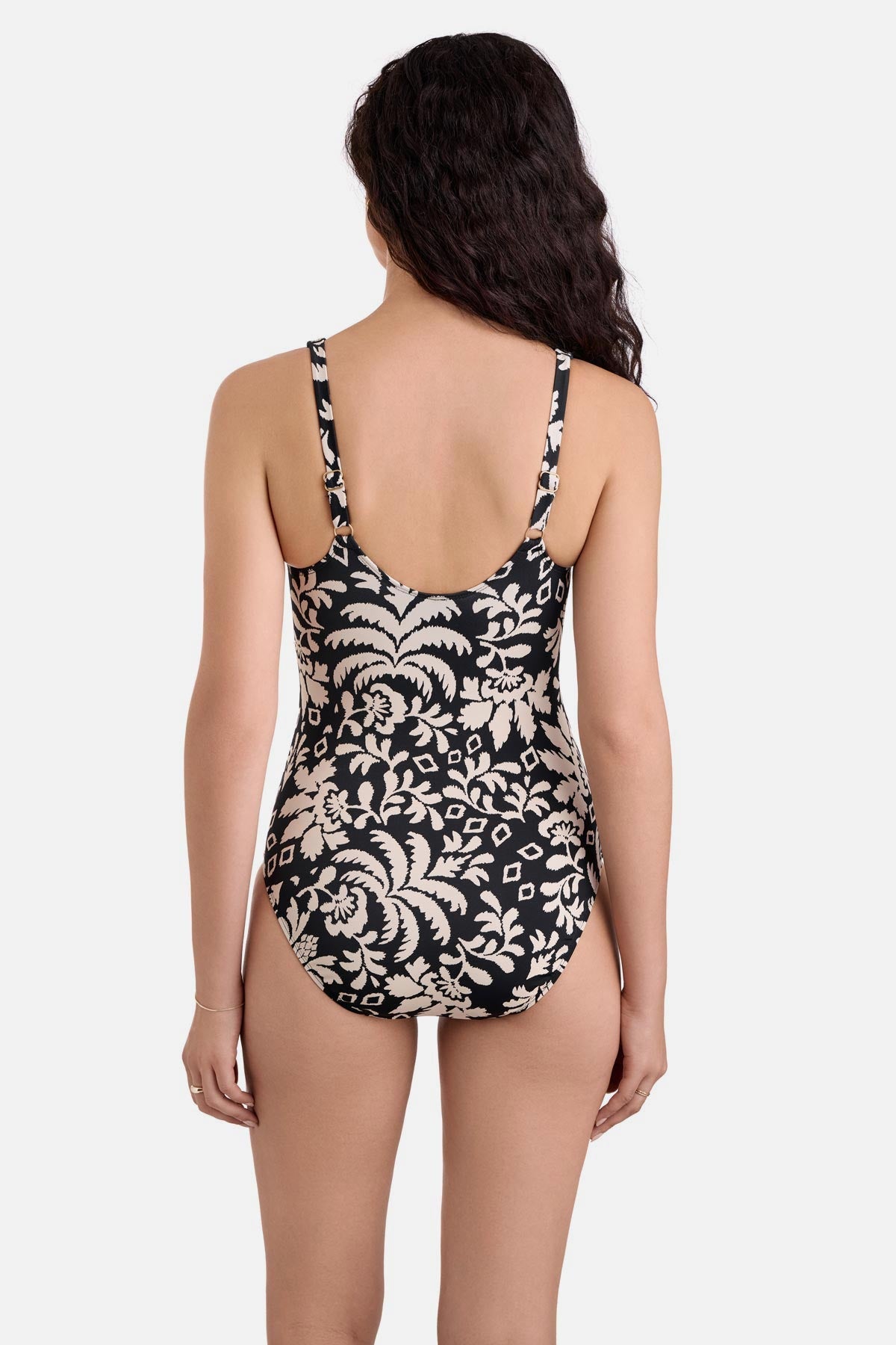 Woman turned away wearing a black and white palm tree printed one-piece swimsuit