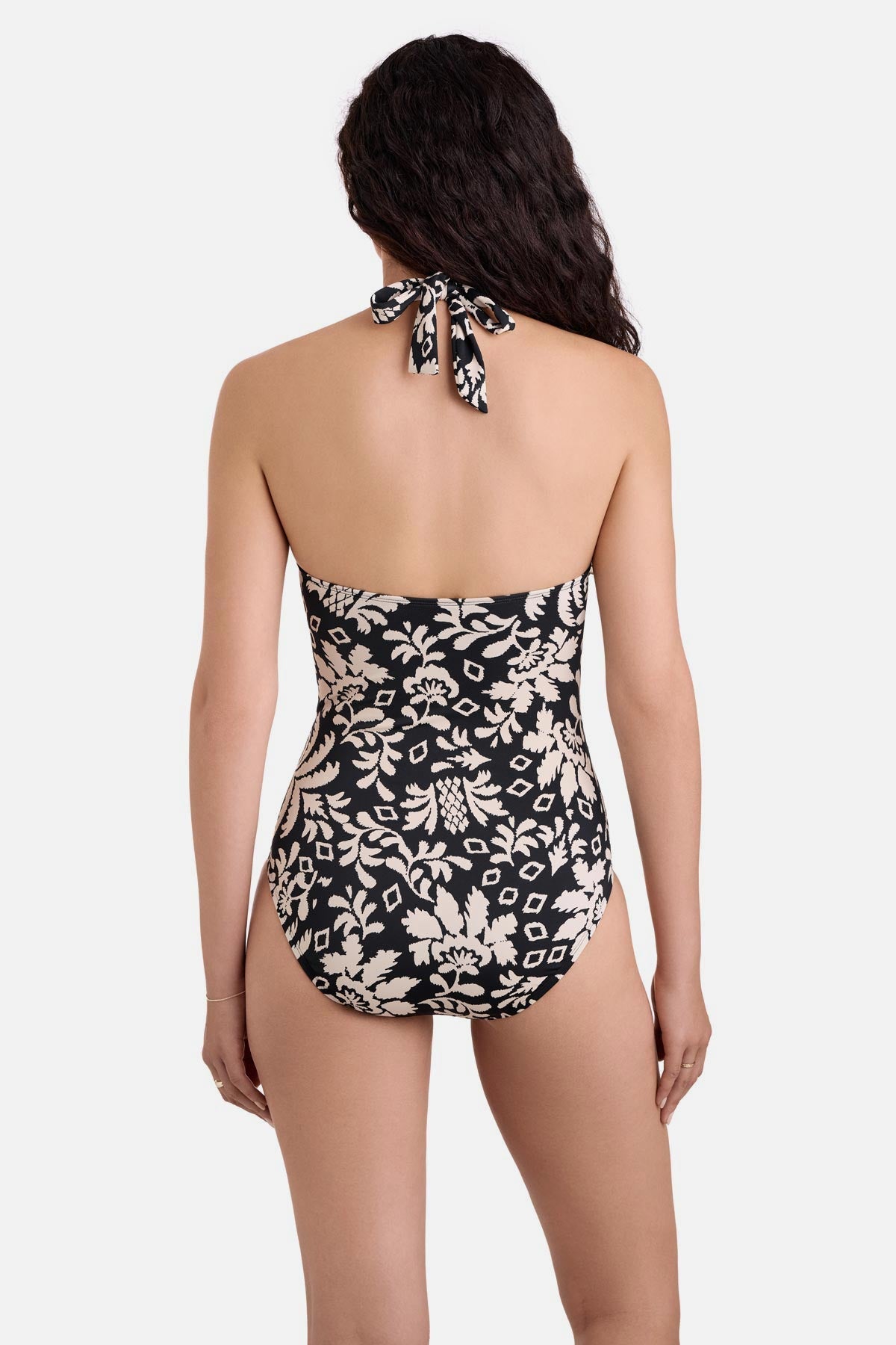 Woman turned away wearing a black and white palm tree printed one-piece swimsuit