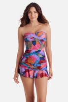 Woman wearing a bandeau style multicolored abstract print tankini top with matching skirted swim bottoms