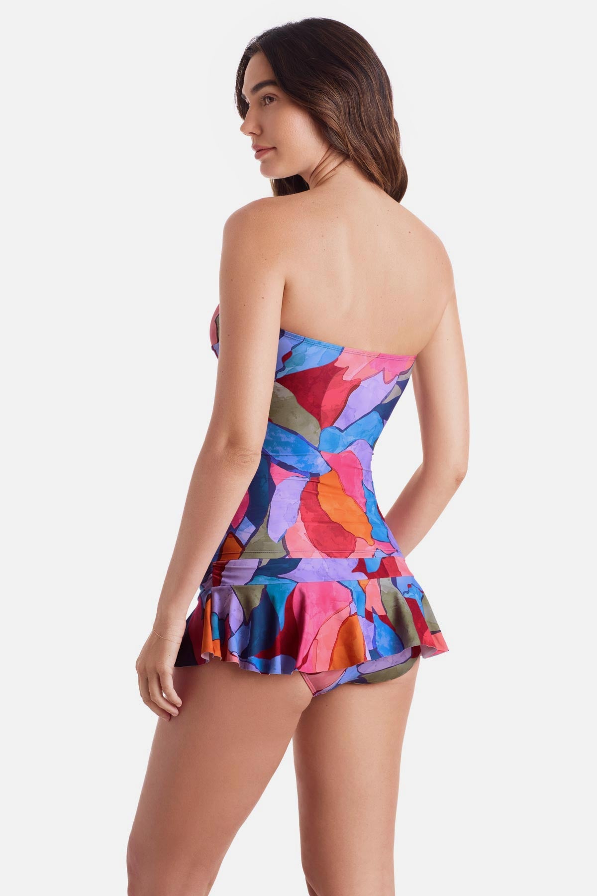 Woman turned left wearing a bandeau style multicolored abstract print tankini top with matching skirted swim bottoms