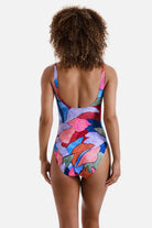 Woman turned away wearing a multicolored abstract print one-piece swimsuit