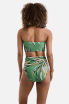 Woman turned away wearing a multicolored leaf print bandeau midkini swim top with matching swim bottoms