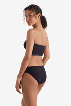 Woman faced left wearing a black midkini swim top with black swim bottoms