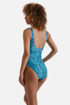 Woman turned left wearing a blue abstract printed one-piece swimsuit