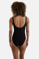 Woman turned away wearing a black one-piece swimsuit with a scoop back