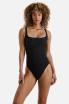 Woman wearing a black one-piece swimsuit with a square neckline