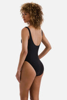 Woman turned left wearing a black one-piece swimsuit with a square neckline