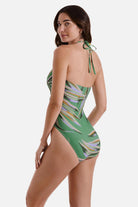 Woman turned left wearing a multicolored leaf printed one-piece swimsuit with a halter tie