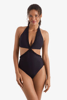 Woman wearing a black one-piece swimsuit with cut outs on each side
