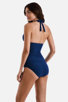 Woman turned left wearing a dark blue halter tankini top with matching swim bottoms