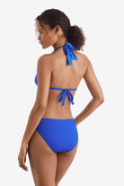 Woman faced left wearing a blue bikini top with matching swim bottoms