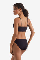 Woman faced left wearing a black midkini swim top with black swim bottoms