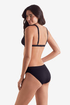 Woman faced left wearing a black bikini top with black swim bottoms