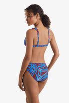 Woman turned left wearing a blue and brown abstract printed bikini top with match swim bottoms