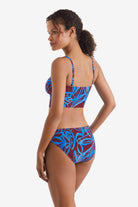 Woman faced left wearing a blue and brown abstract floral printed midkini swim top with matching swim bottoms
