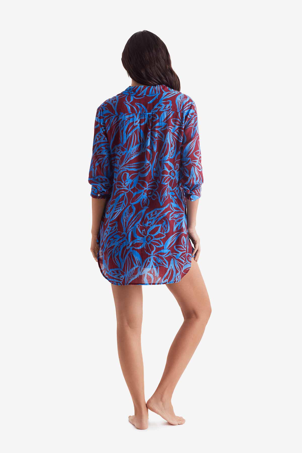 Woman turned away wearing a button down long sleeve shirt with blue and brown abstract floral print