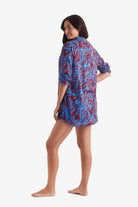 Woman turned left wearing a button down long sleeve shirt with blue and brown abstract floral print