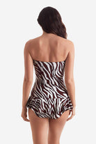 Woman turned away wearing a zebra print one piece swimsuit with skirted leg