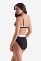 Women turned left wearing a black and white bikini top and black and white swim bottoms