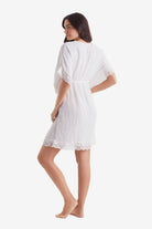 Woman faced left wearing a white tunic dress