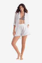 Woman wearing a white long sleeve button up shirt unbuttoned