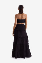 Woman turned away wearing a black bandeau top and black floor length skirt