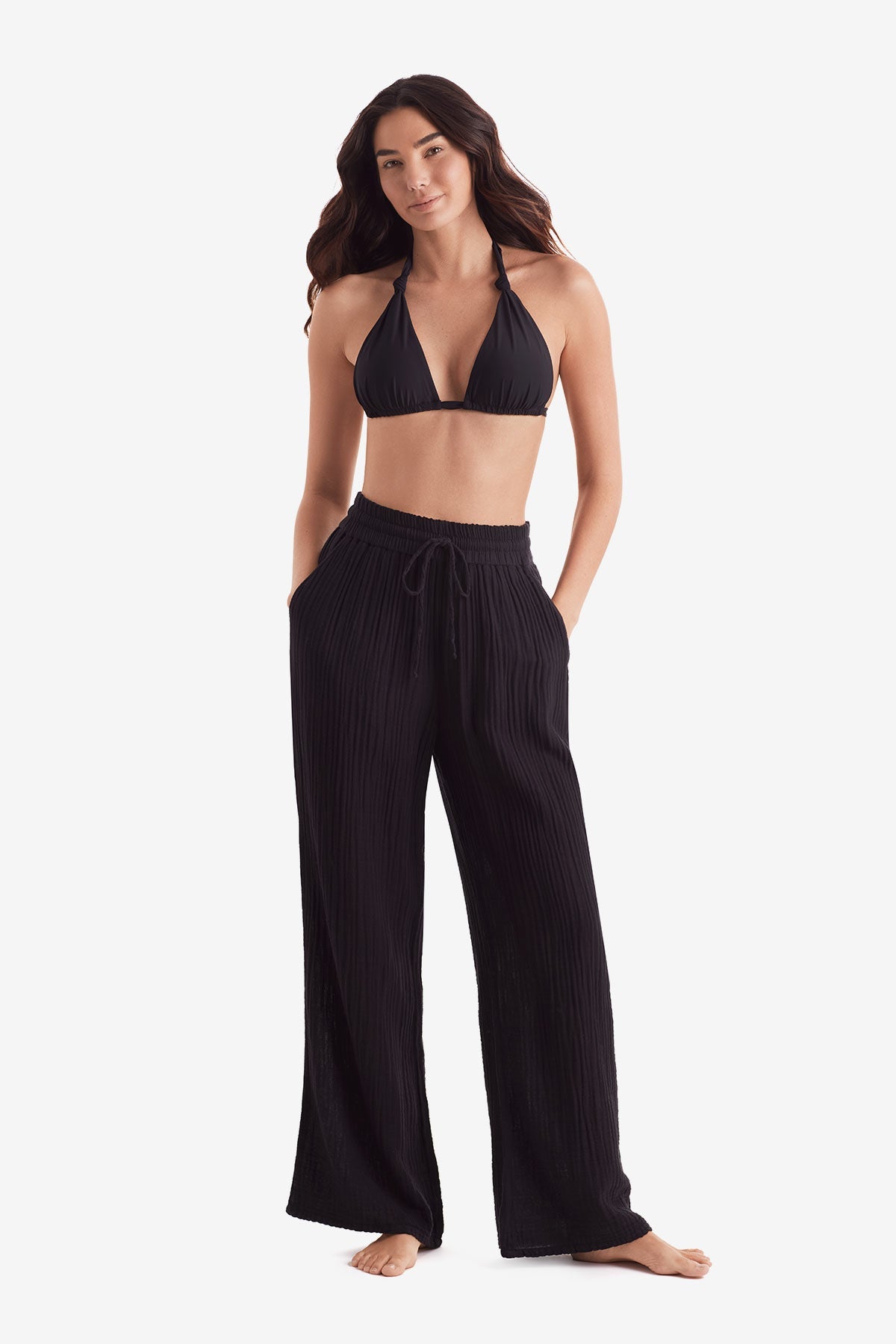 Woman wearing a black bikini top and black beach pants