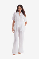 Woman wearing a white short sleeve button up and white beach pants