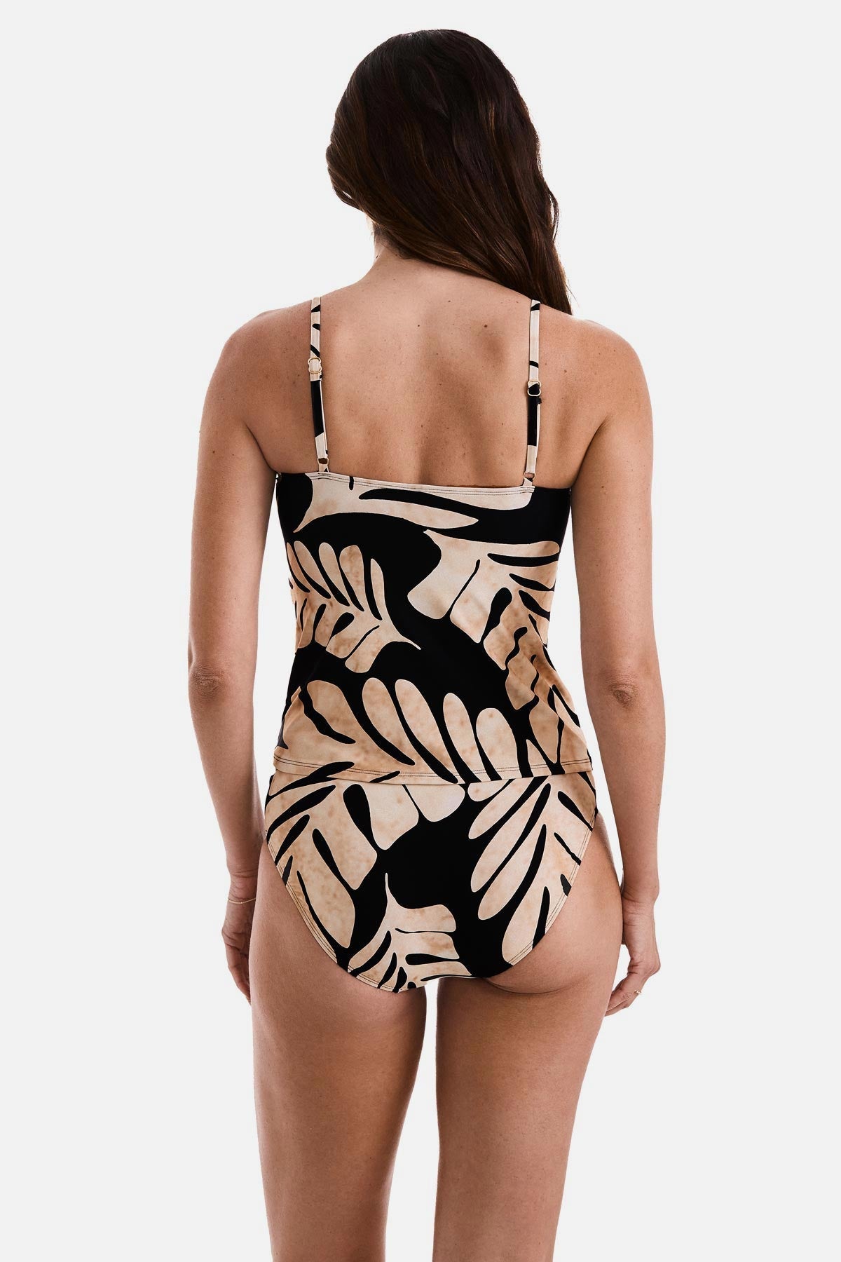 Woman turned away wearing a large tan and black leaf printed tankini top with matching swim bottoms