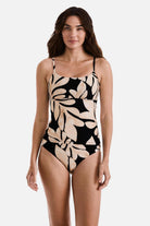 Woman wearing a large tan and black leaf printed tankini top with matching swim bottoms