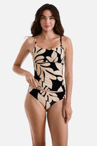 Woman wearing a large tan and black leaf printed tankini top with matching swim bottoms