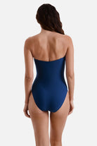 Woman faced away wearing a dark blue one-piece swimsuit 