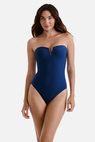 Woman wearing a dark blue one-piece swimsuit with a sweetheart neckline