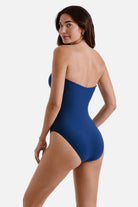 Woman faced left wearing a dark blue one-piece swimsuit with a sweetheart neckline