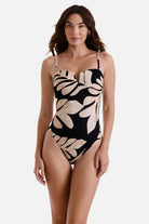 Woman wearing a one-piece swimsuit with a black and tan palm leaf print 