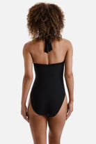 Woman turned away wearing a black  one-piece swimsuit with frills along the edges