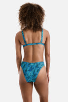 Woman turned away wearing a blue abstract printed bikini top with matching swim bottoms