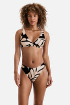 Woman wearing a large black and tan palm leaf printed bikini top with matching swim bottoms