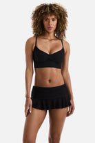 Woman wearing a black midkini tankini swim top with matching skirted swim bottoms